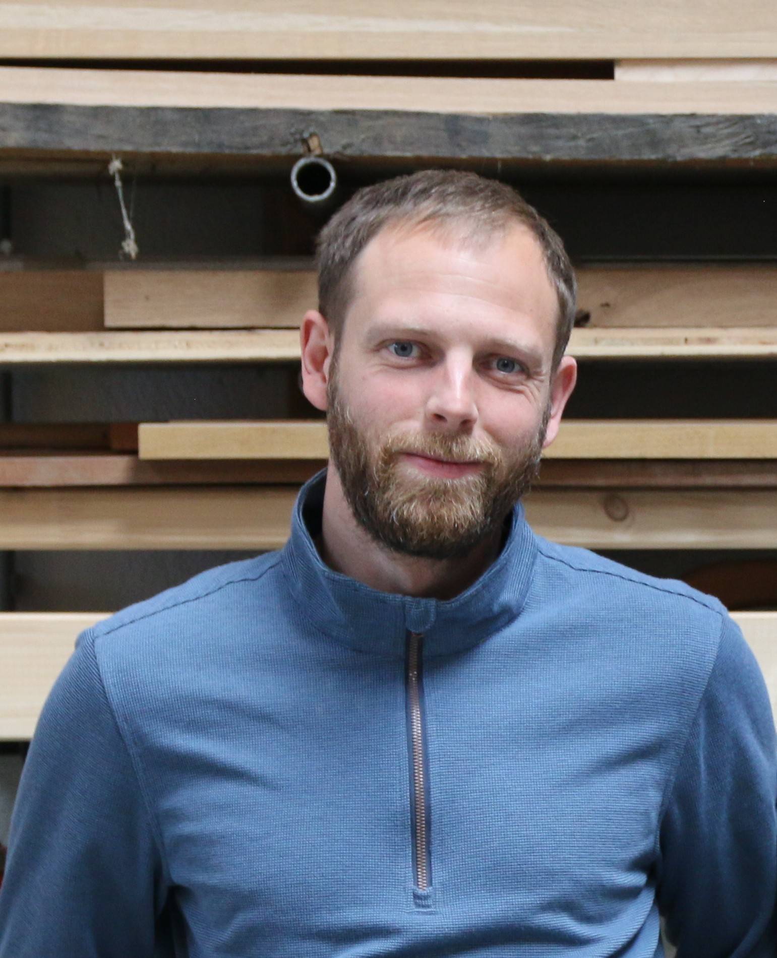 Mann in blauer Jacke vor Holz