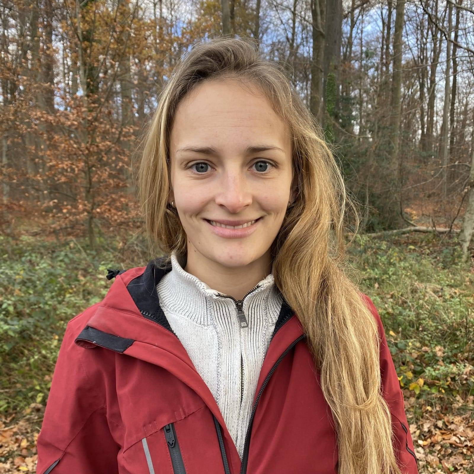 Frau im Wald mit rotem Mantel.